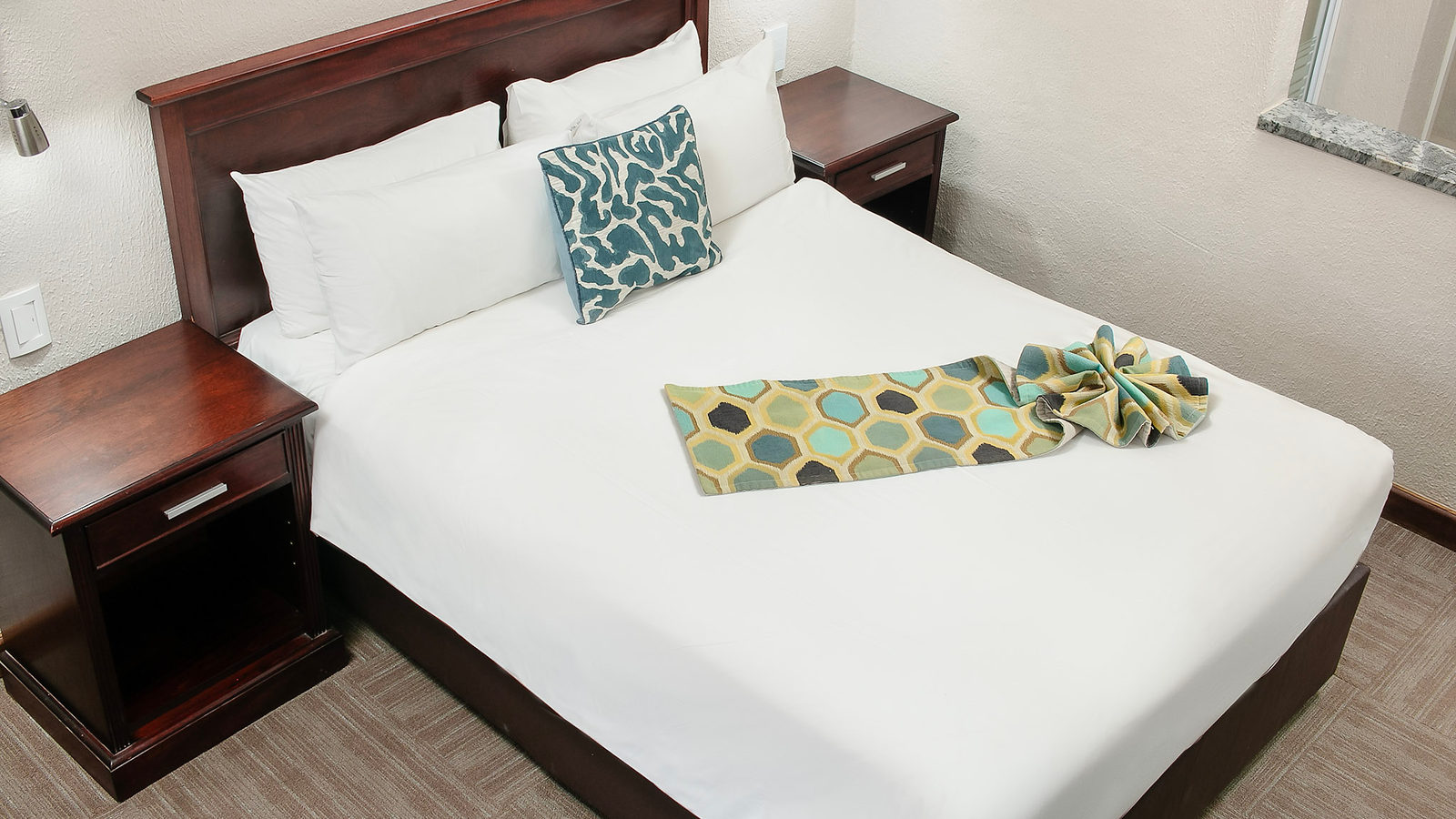 A made-up bed with teal cushions in a Hotel 247 room