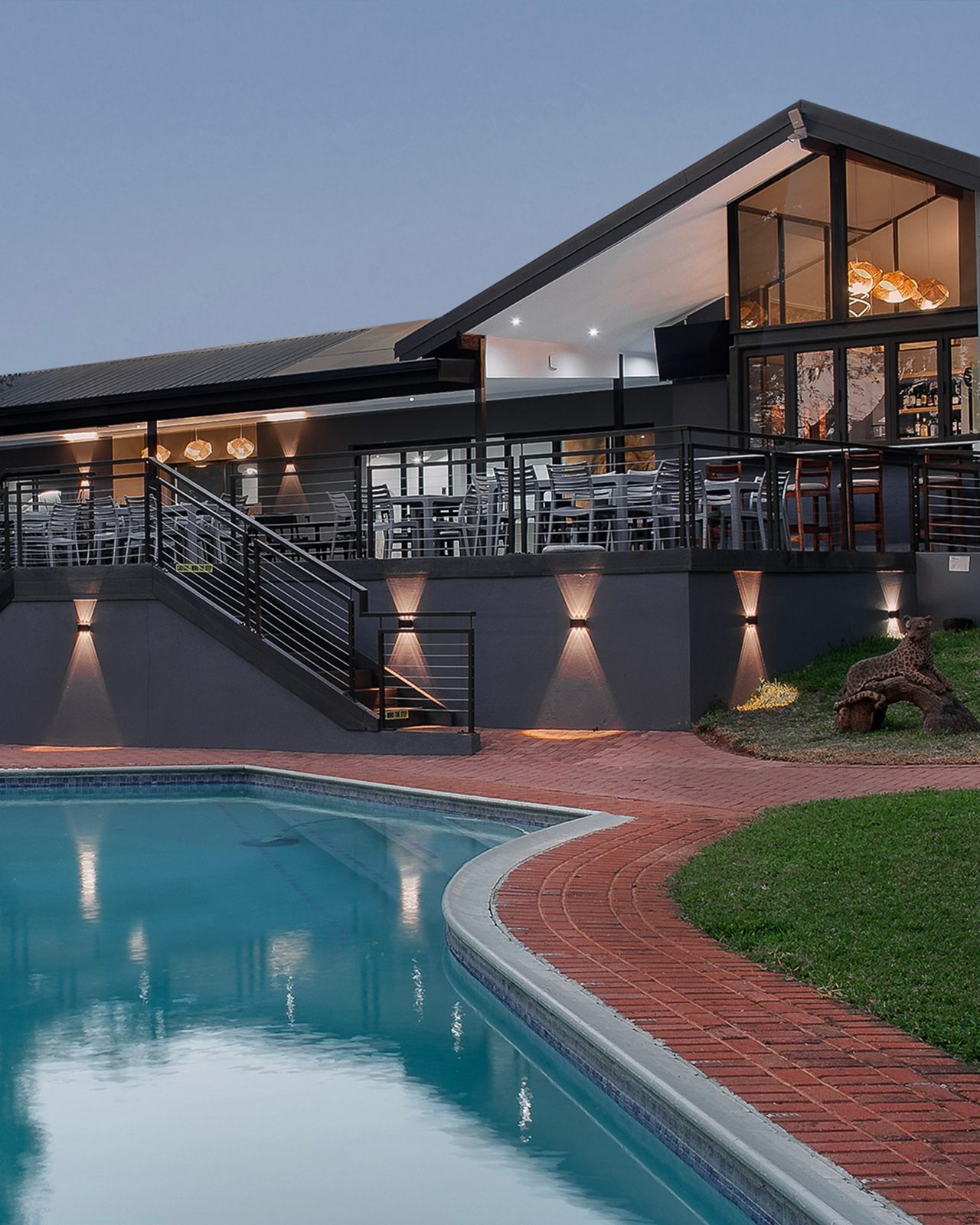 TAU Restaurant & Bar at dusk, with its lit deck and glass walls above the hotel pool